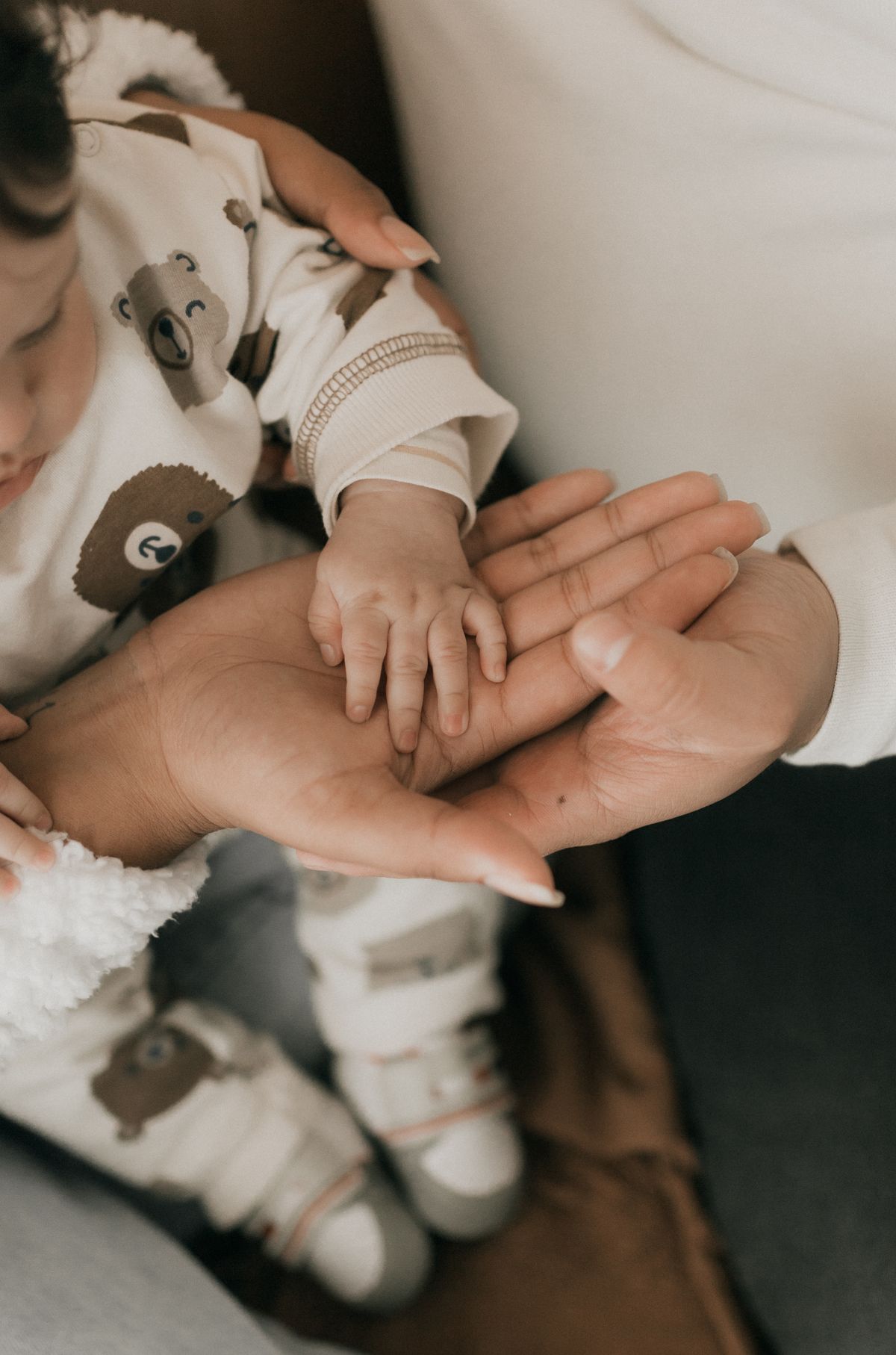 A parent holding a baby’s hand, illustrating care during early childhood