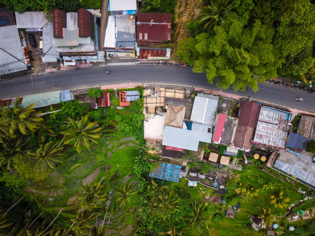An aerial view of a Balinese village and rice fields, illustrating local development planning